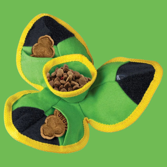 Green shamrock-shaped pet toy with a yellow rim and black interior, filled with treats on a white background.